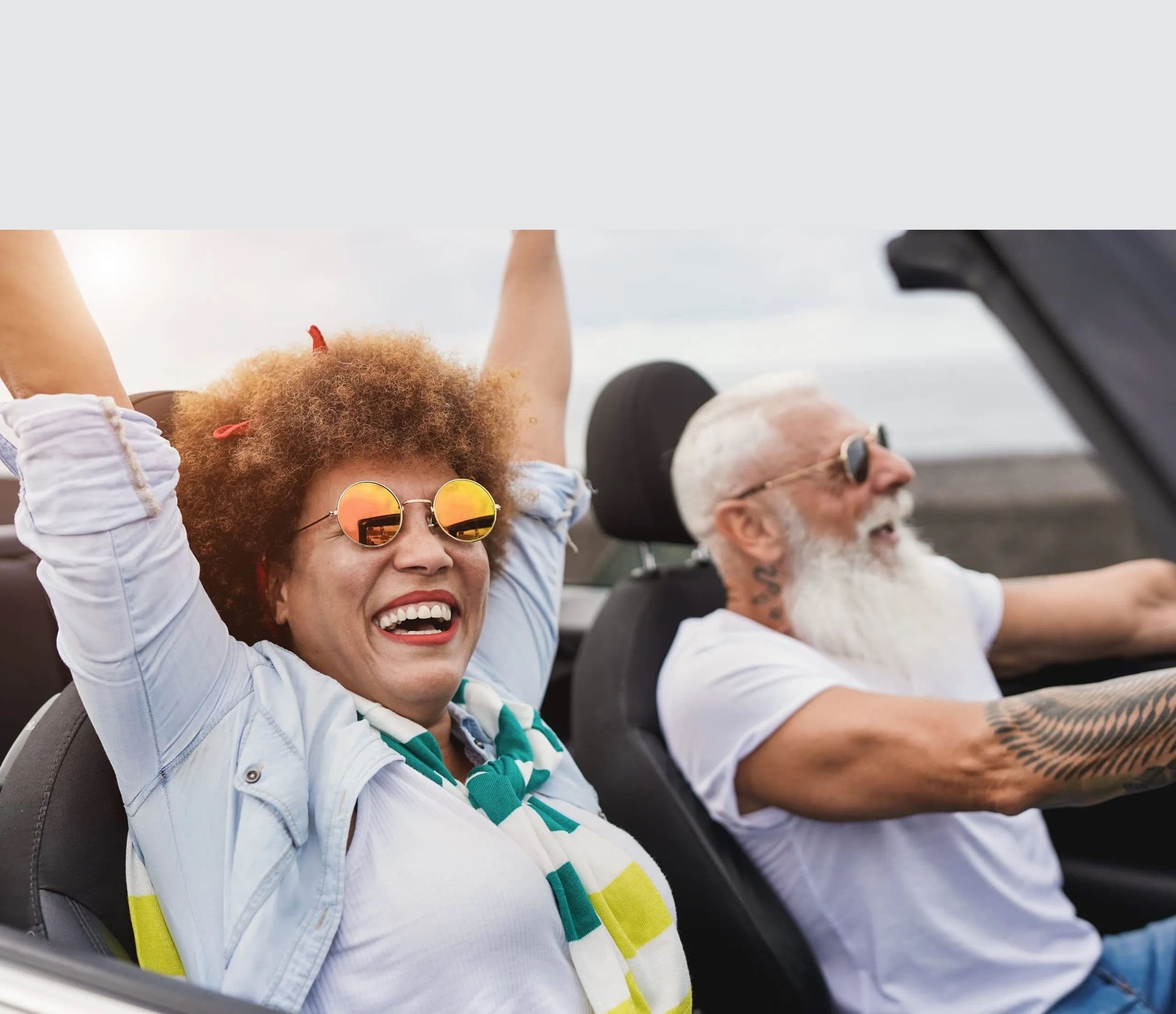 A joyful senior couple laughing together in a convertible car
