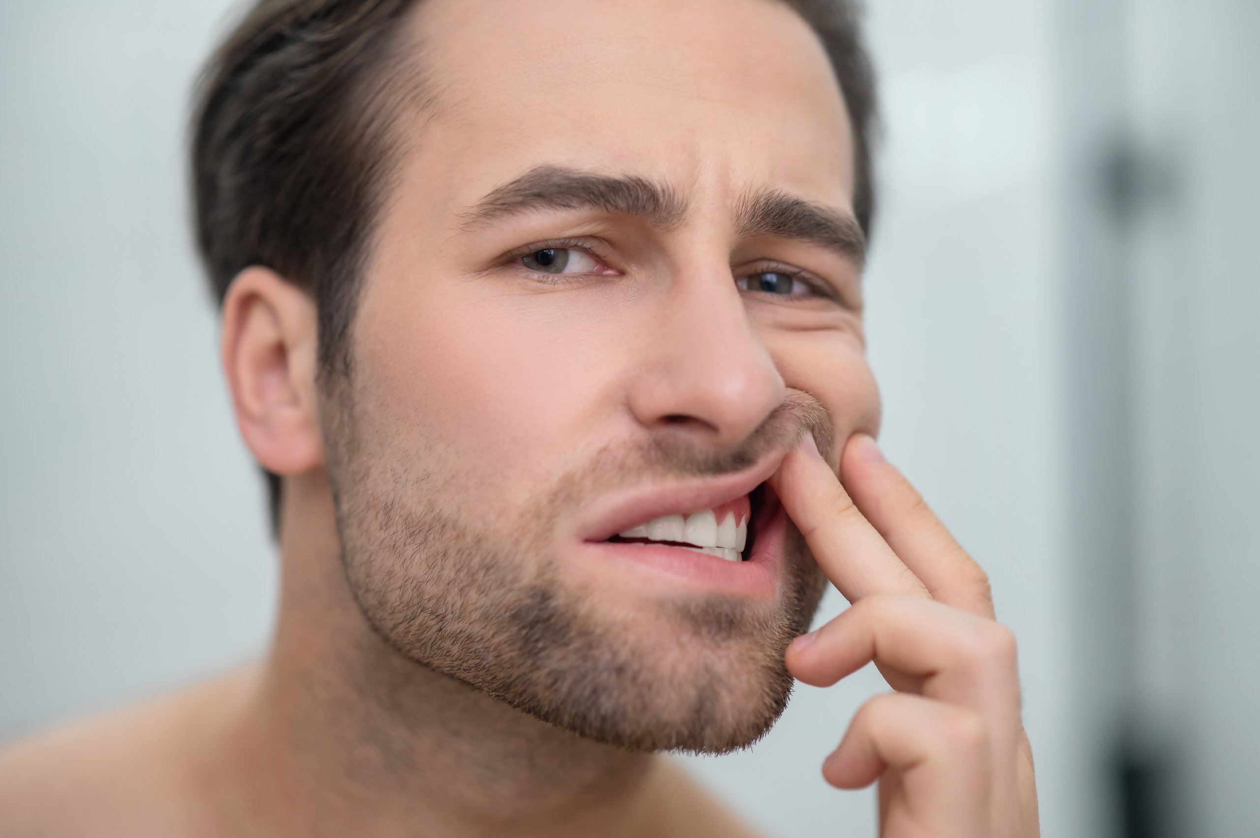 A man looking disturbed while checking a chipped tooth